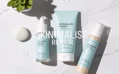 Three minimalist skincare products—a ceramide barrier serum, a skinimalist repair cream, and a minimal SPF 30 sunscreen—arranged on a white marble surface with water droplets and a small green succulent. The text "SKINIMALIST REPAIR" is overlaid on the image, representing a focus on essential, gentle skincare for a damaged barrier.